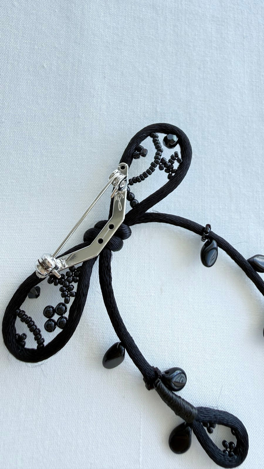 Back view of the black ribbon brooch showing the brass pin