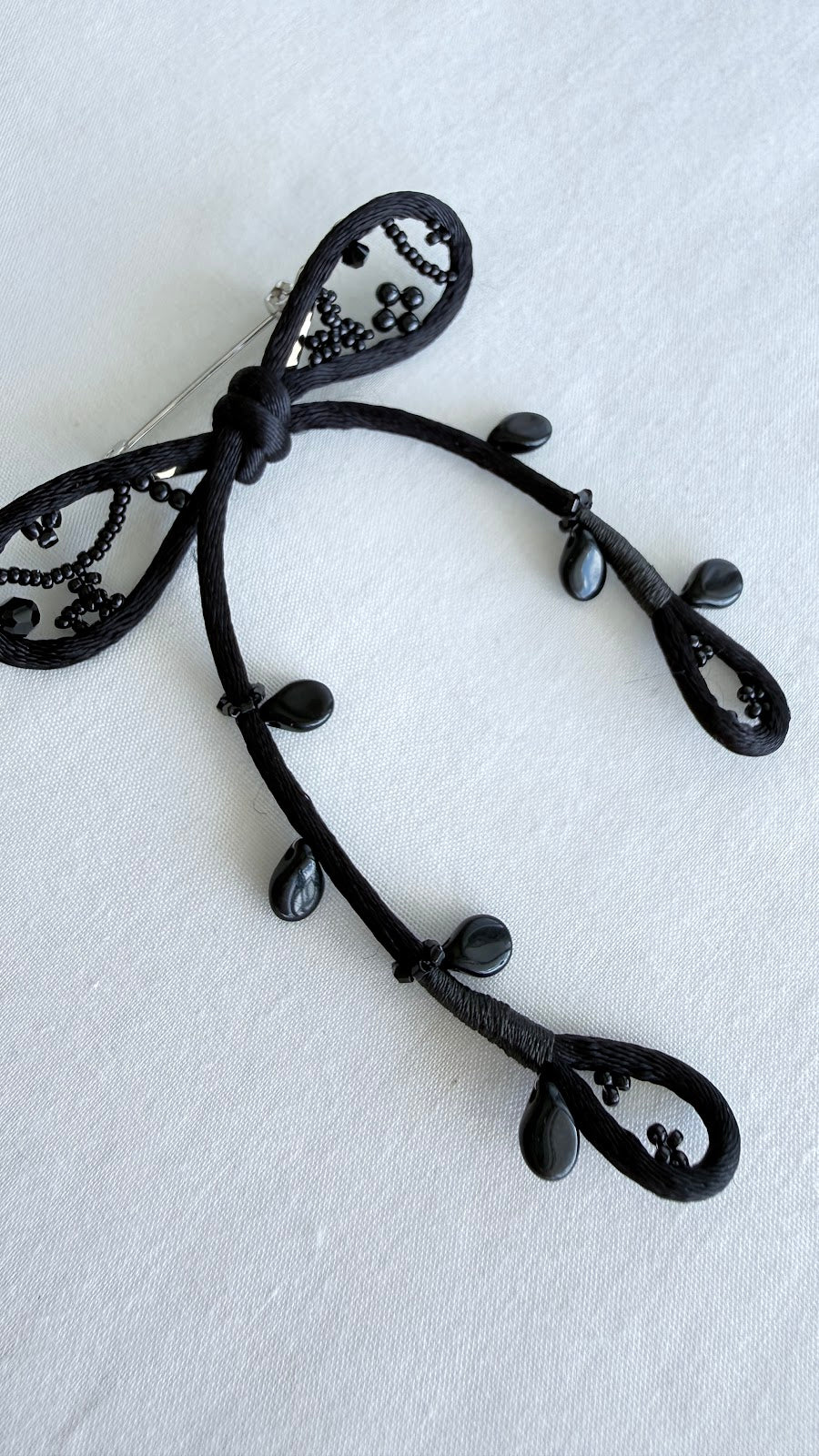 Black ribbon brooch by certified artisan Saito, flat lay detail view