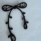 Black ribbon brooch close-up showing bead and cord detail